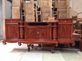 Kệ tivi cột nho với họa tiết đơn giản, bề mặt nhẵn tôn lên vẻ đẹp vân gỗ Hương đá lâu năm.