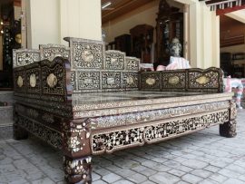 Bộ sập được làm từ gỗ gụ mật, dài 1m8x2m, gồm 2 món (1 giường, 1 bệ chân), khảm tứ diện bằng ốc xà cừ đỏ lửa vàng tranh lấp lánh